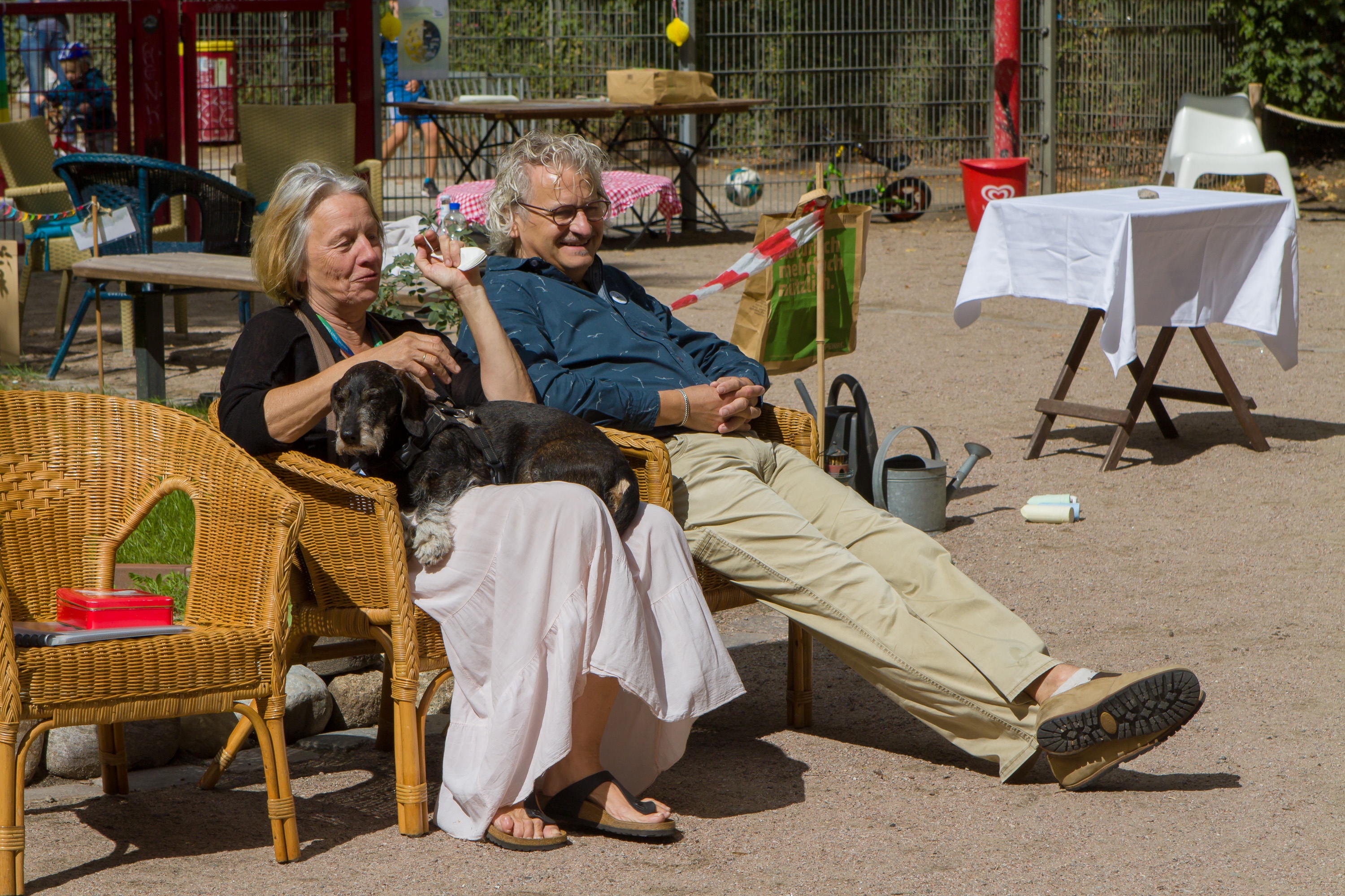 Ein Mann und eine Frau sitzen auf Stühlen im Eingangsbereich des Stephanusgartens in der Sonne