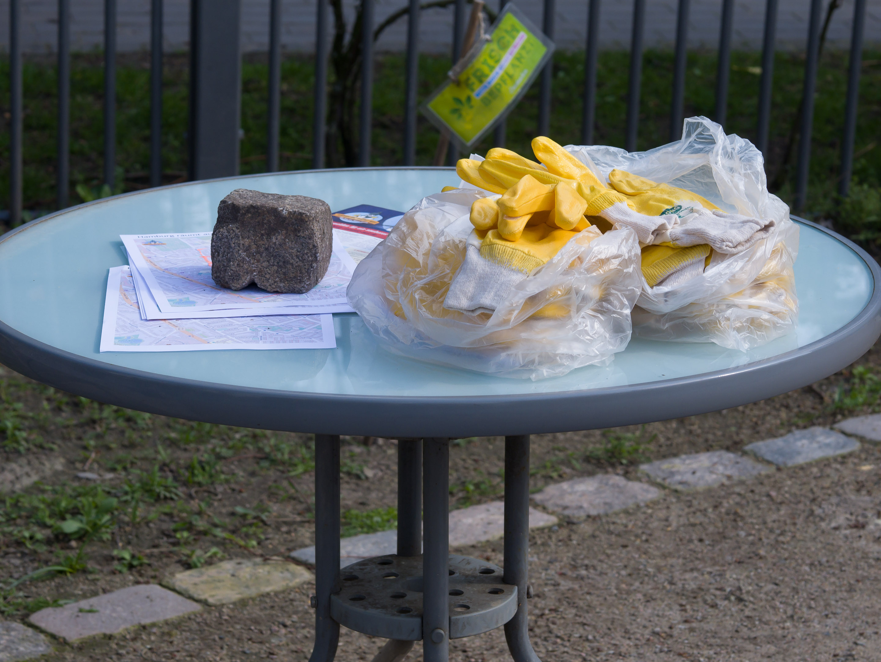 Standtpläne, Infomaterial und gelbe Gummihandschuhe auf einem runden Tisch